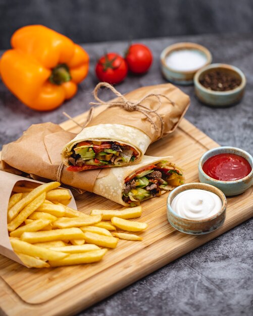 Beef burrito with tomato cucumber lettuce jalapeno served with fries and sauces vertical