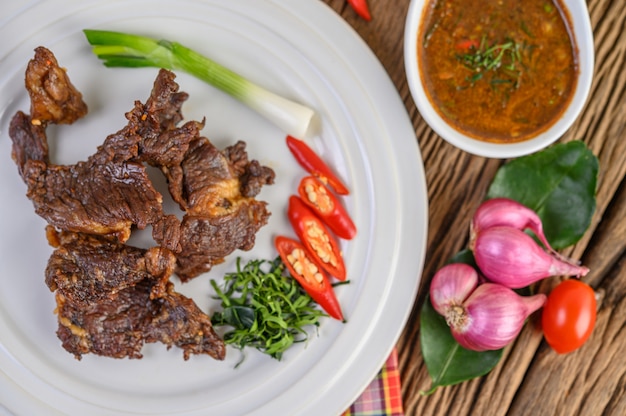 Free photo beef fried thai food on a white plate with spring onion, kaffir lime leaves, chilies, red onions and tomatoes.