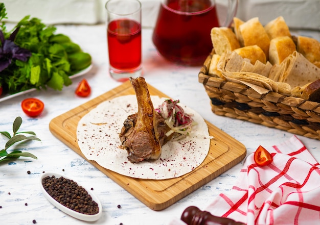 Beef lamb chop meal in lavash on wooden plate with onion salad , bread, vegetabels and wine