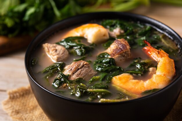 Beef, okra stew and spinach in bowl on wooden table