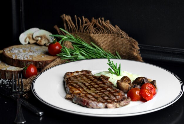 Beef steak served with rice, mushroom and tomato