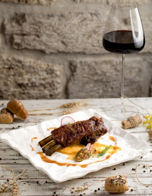 Beef steak with sauce and a glass of red wine in a white plate.