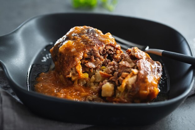 Beef stew ball with vegetable feeling in sauce on dark plate. Closeup