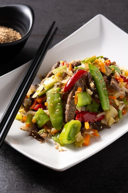 Beef vegetables and sesame seeds in white plate on black background