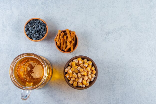 Beer glass and bowl of croutons chickpea, seed , on the marble background.