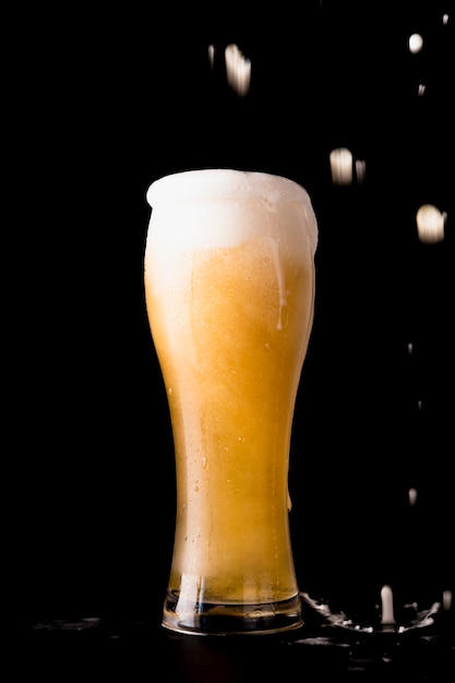 Beer glass in front of black background