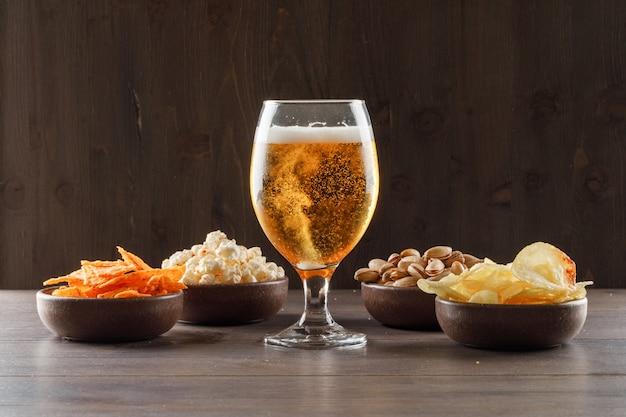 Beer in a goblet glass with junk food side view on a wooden table