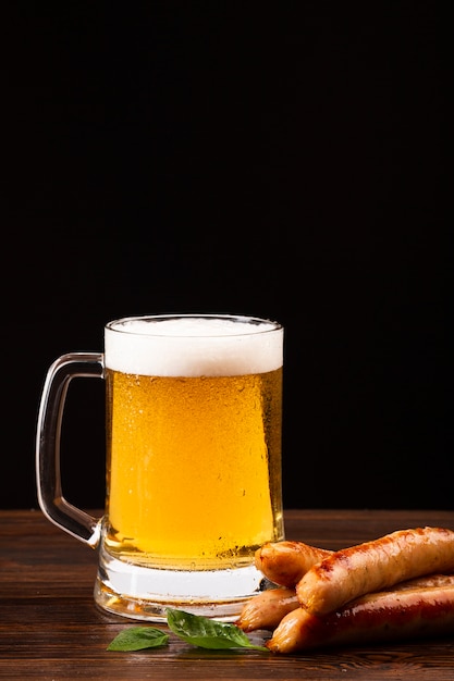 Free photo beer mug and sausages on wooden board