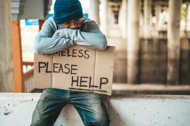 Free Photo beggars sit on barriers with homeless please help messages.