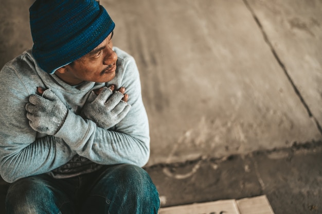 Free photo the beggars sit under the bridge with a homeless message. please help.