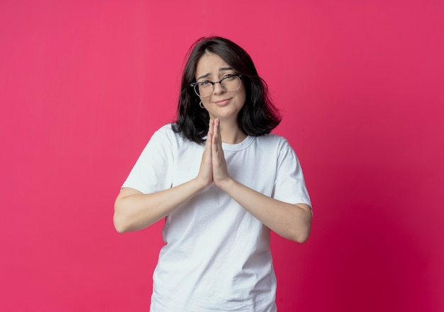 Free photo begging young pretty girl wearing glasses putting hands together in pray gesture