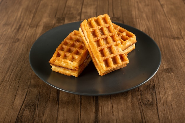 Belgian waffles in a saucer on a wooden table.