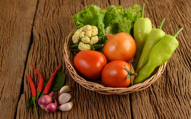 Bell pepper, tomato, Onion, salad, chili, Shallot, garlic, cauliflower, and kaffir lime leaves on a wooden basket on wood table