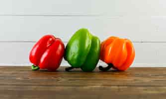 Free photo bell peppers on dark and white wooden surface, side view.