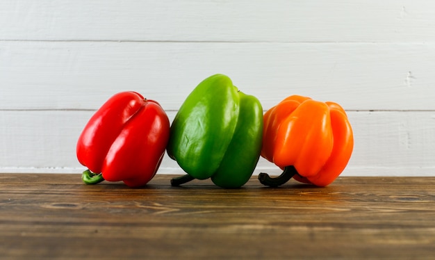 Bell peppers on dark and white wooden surface, side view.