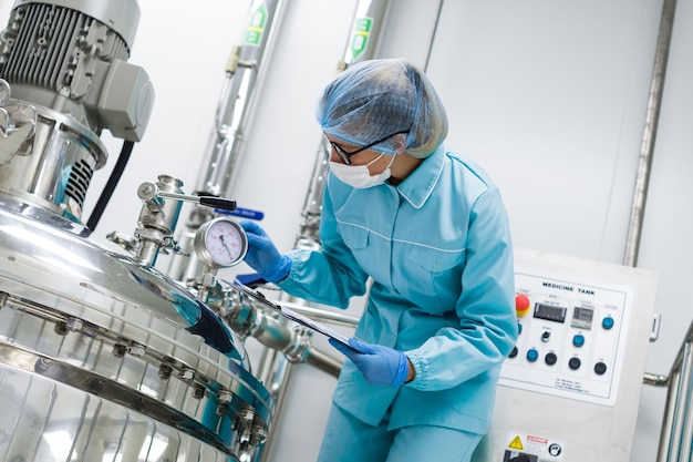 Free Photo bended scientist in blue lab uniform check how compressor tank works tablet in hands close