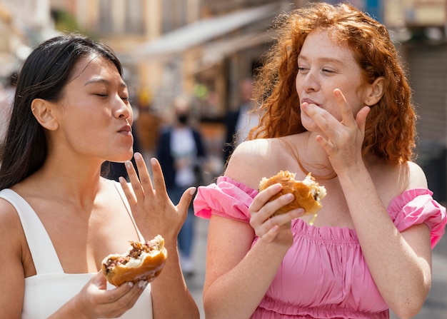 Free photo best friends eating together some street food