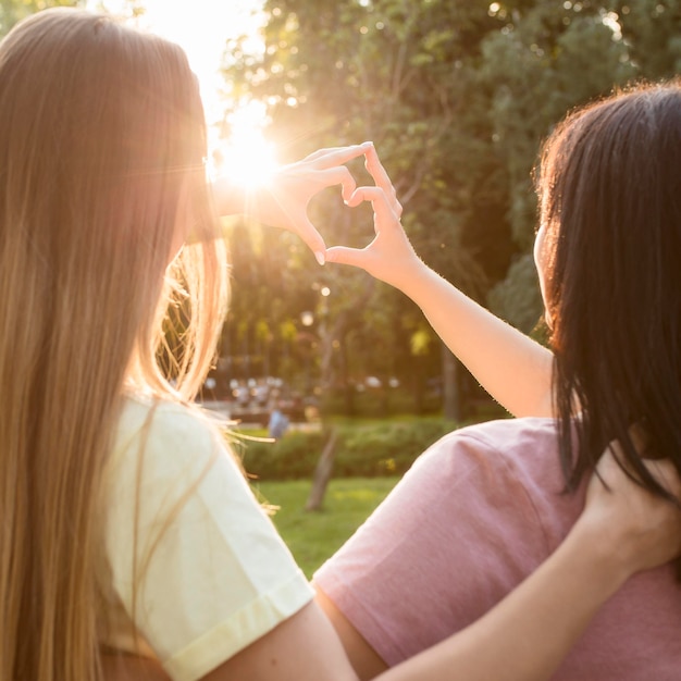 Best friends making a heart on sunlight