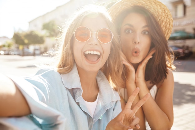 Free Photo best friends wearing stylish outfit and taking selfie on the street