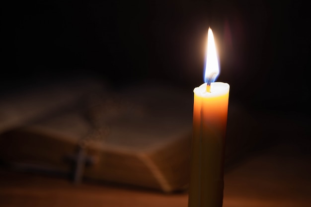 Bible and candle on a old oak wooden table. 