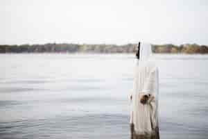 Free photo biblical scene - of jesus christ standing in the water with a blurred background