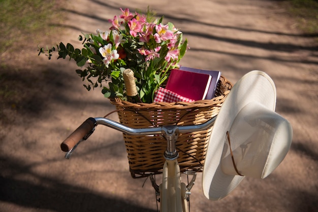 Free photo bicycle basket with flowers and books high angle