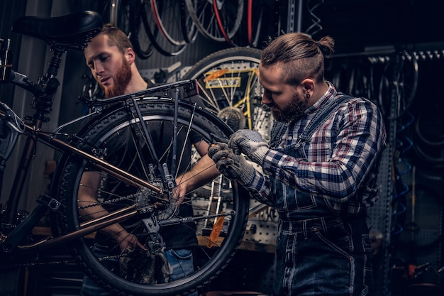 Bicycle mechanic in a workshop with bike parts and wheel on a background.