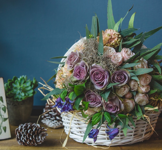 Big basket of mixed flowers standing on a table with christmas cones