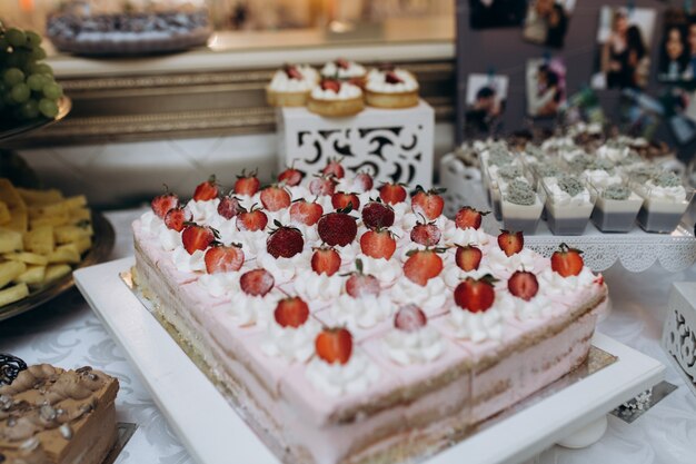 Big biscuit cake with cream and strawberries cutted on portions