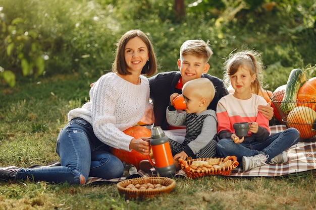 Big family sitting on a garden near many pumpkins