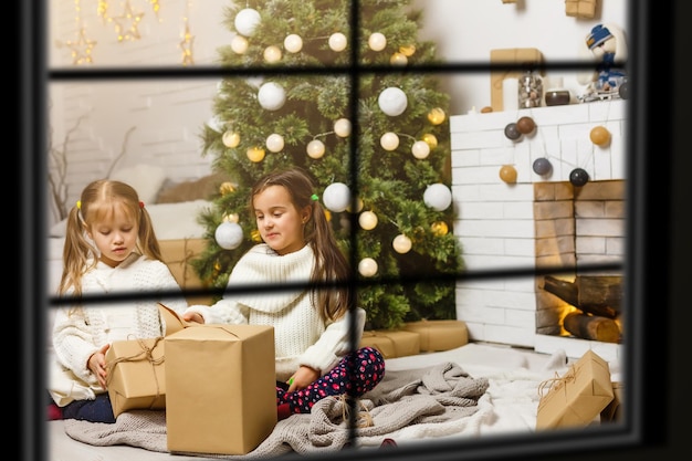 Big family with three children celebrating Christmas at home. Festive dinner at fireplace and Xmas tree. Parent and kids eating at fire place in decorated room. Child lighting advent wreath candle.