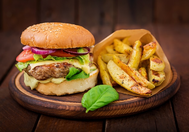 Free photo big sandwich - hamburger with juicy beef burger, cheese, tomato,  and red onion on wooden table