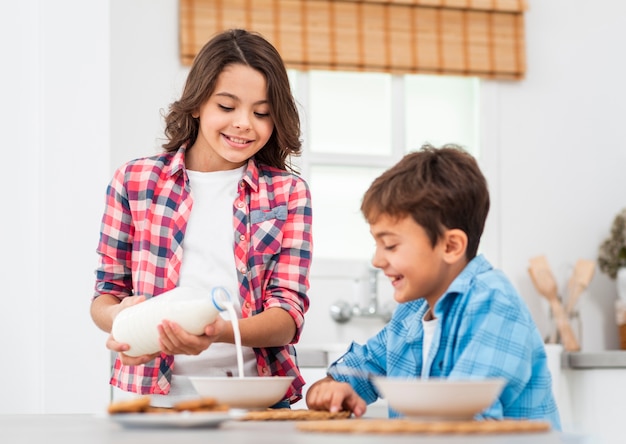 Big sister pouring milk for little brother