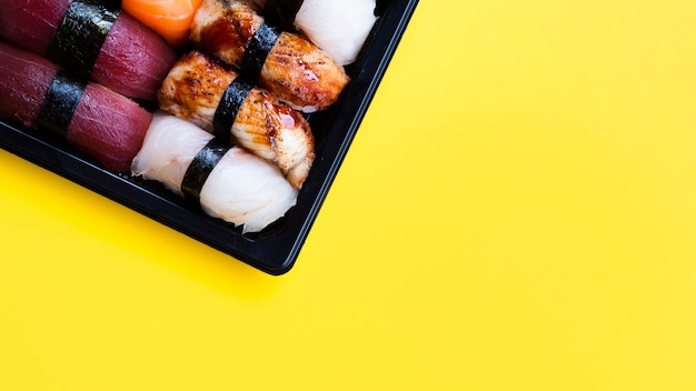 Free Photo big sushi black plate on a yellow background