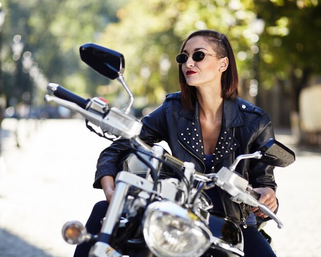 Biker girl in a leather jacket on a motorcycle