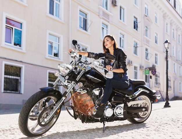 Biker girl in a leather jacket on a motorcycle