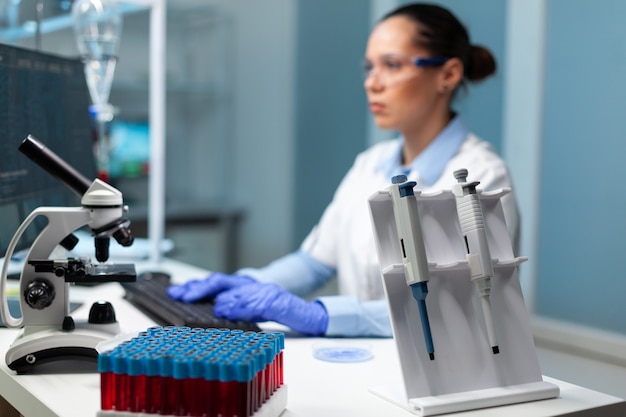 Free photo biologist researcher woman with white coat discovering vaccine against virus typing medical expertise on computer. professional modern equipment standing on table in hospital laboratory