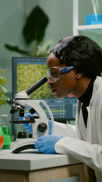 Biologist woman examining biological slide for medical expertise using microscope