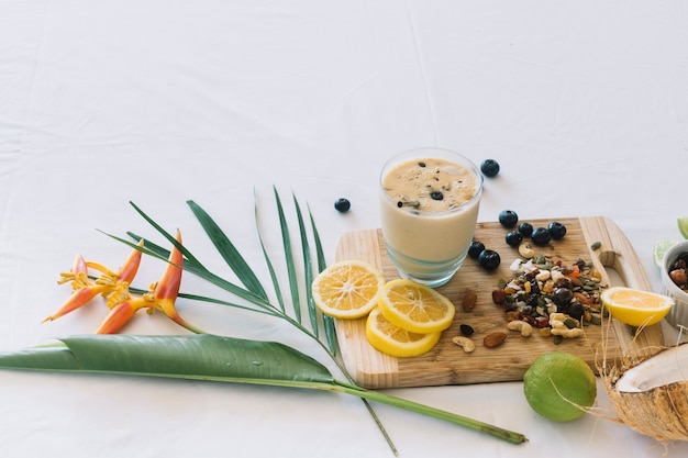 Free photo bird of paradise flower; smoothie with dryfruits and citrus fruits on white background