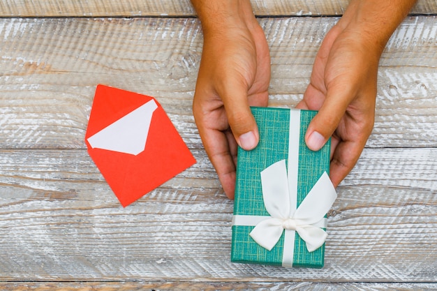 Birthday concept with card in envelope on wooden background flat lay. man passing gift box.