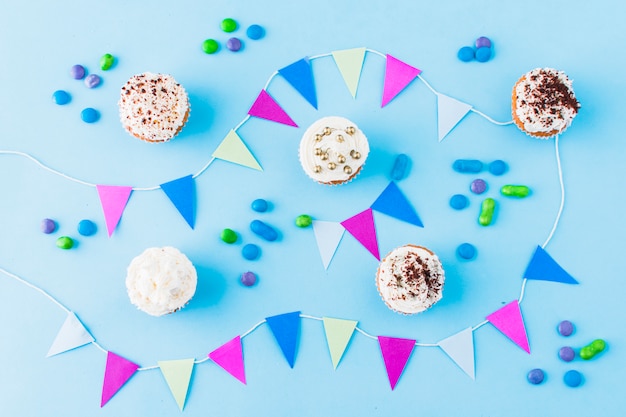 Free photo birthday concept with cupcakes; candies and bunting on blue background