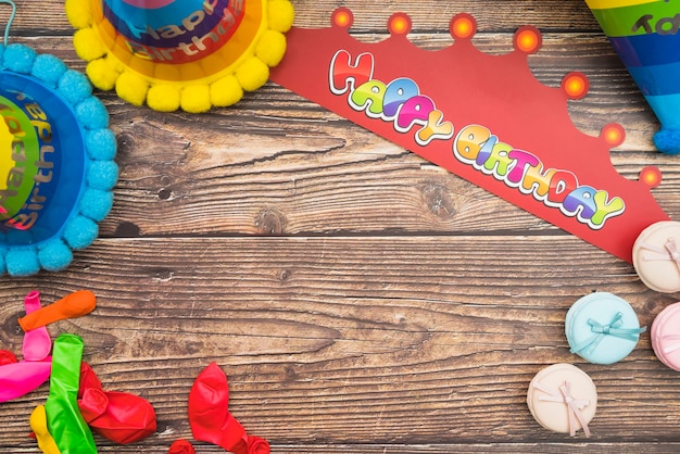 Birthday hat; crown; balloons and macarons on wooden background