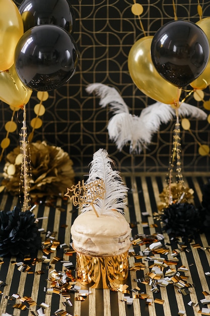 Birthday party cake with golden and black decor various balloons.