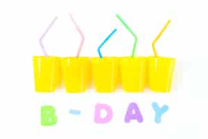 Free photo birthday text with yellow plastic glasses and colorful drinking straws