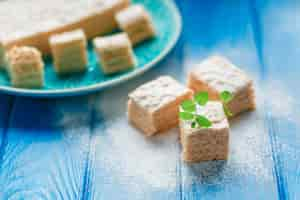 Free photo biscuit cake pie apple candy pastila, mint leaves on blue wood cutting board background.