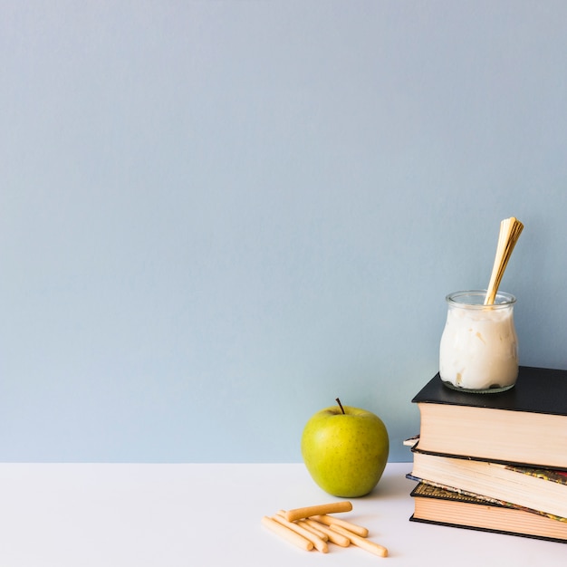 Biscuit sticks and apple near books and yogurt