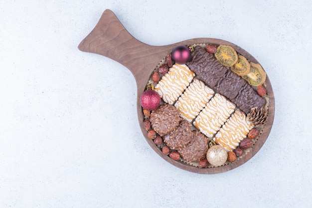 Biscuits, dried fruits and Christmas balls on wooden board. 