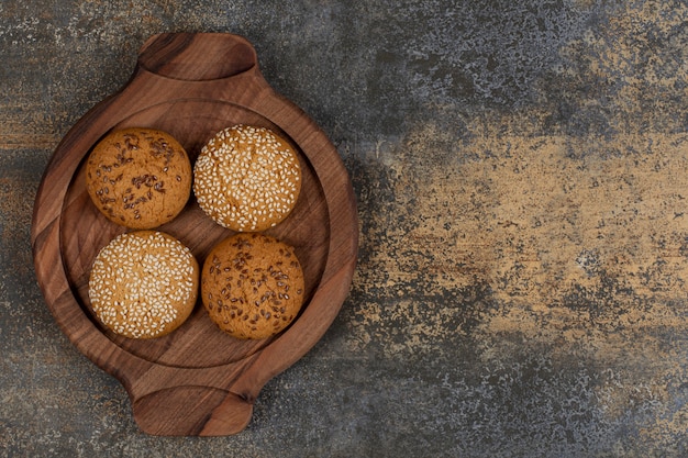 Free photo biscuits with sesame seeds and chocolate pieces on wooden board.