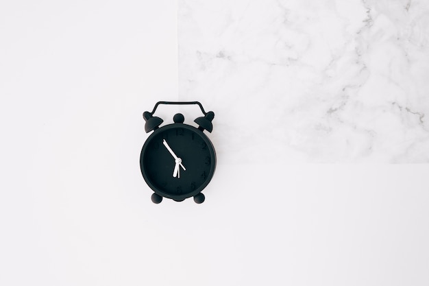 Black alarm clock on white texture background