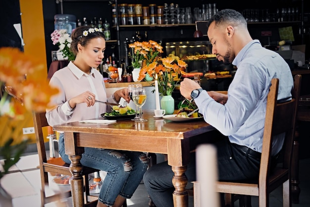 Black American male and female eating vegan food in a restaurant.